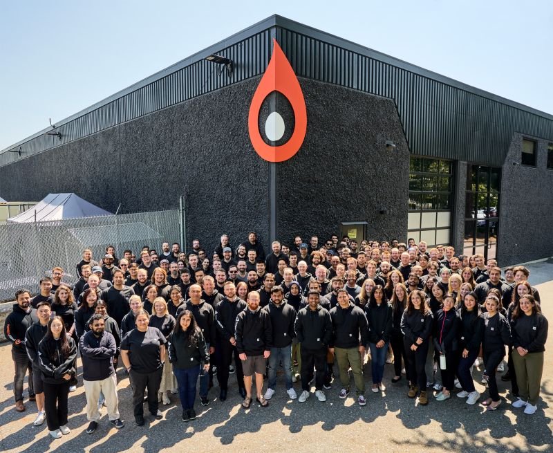 The DarkVision team gathered outside their building beneath the large orange droplet logo
